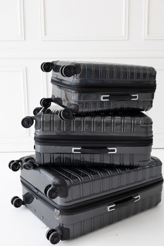 Three black suitcases stacked in a bright studio